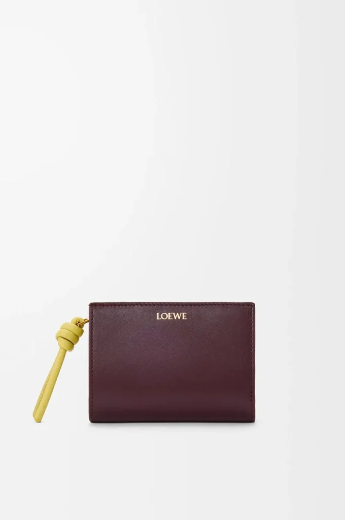Cartera compacta con nudo en piel de becerro napa brillante Burdeos oscuro/Citrino claro Cartera compacta con nudo en piel de becerro napa brillante Burdeos oscuro/Citrino claro